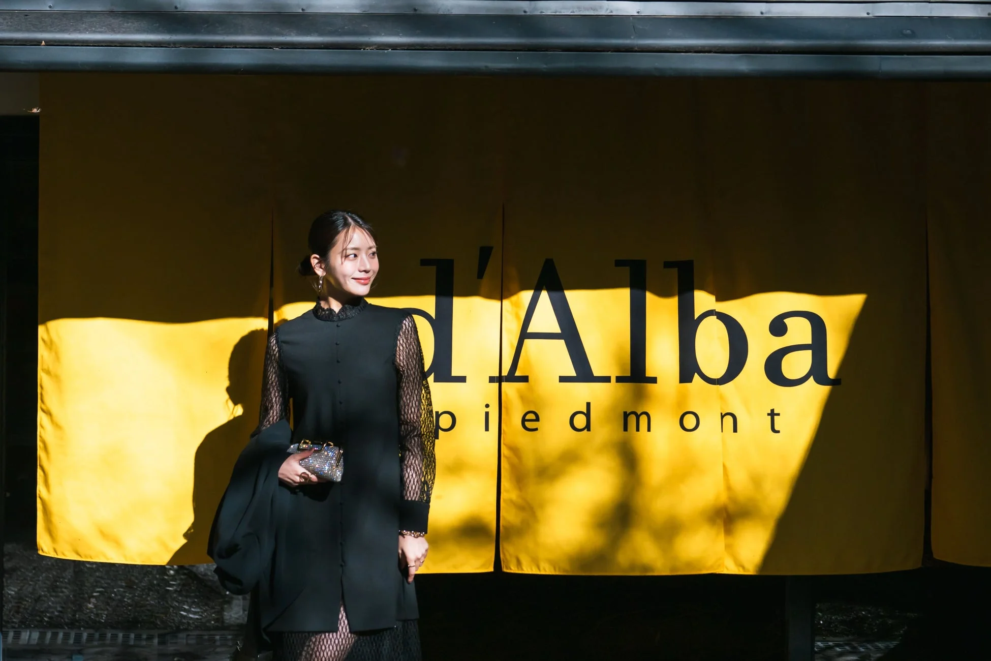 d'Albaロゴ幕の前で女性