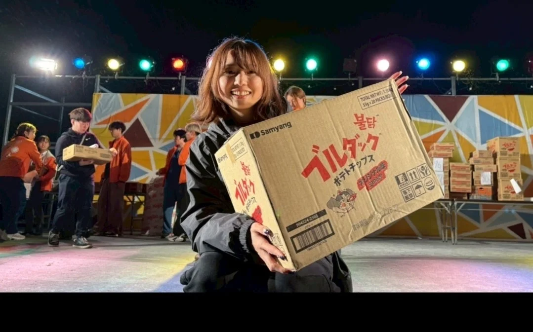 笑顔の女性がブルダックポテトチップスの箱を抱える様子