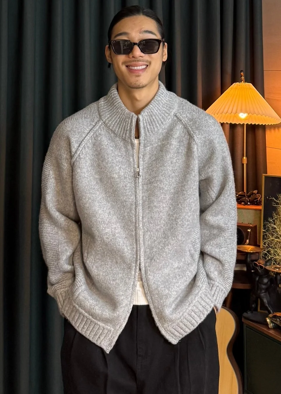 男性がグレーのジップアップカーディガンとサングラスを着用