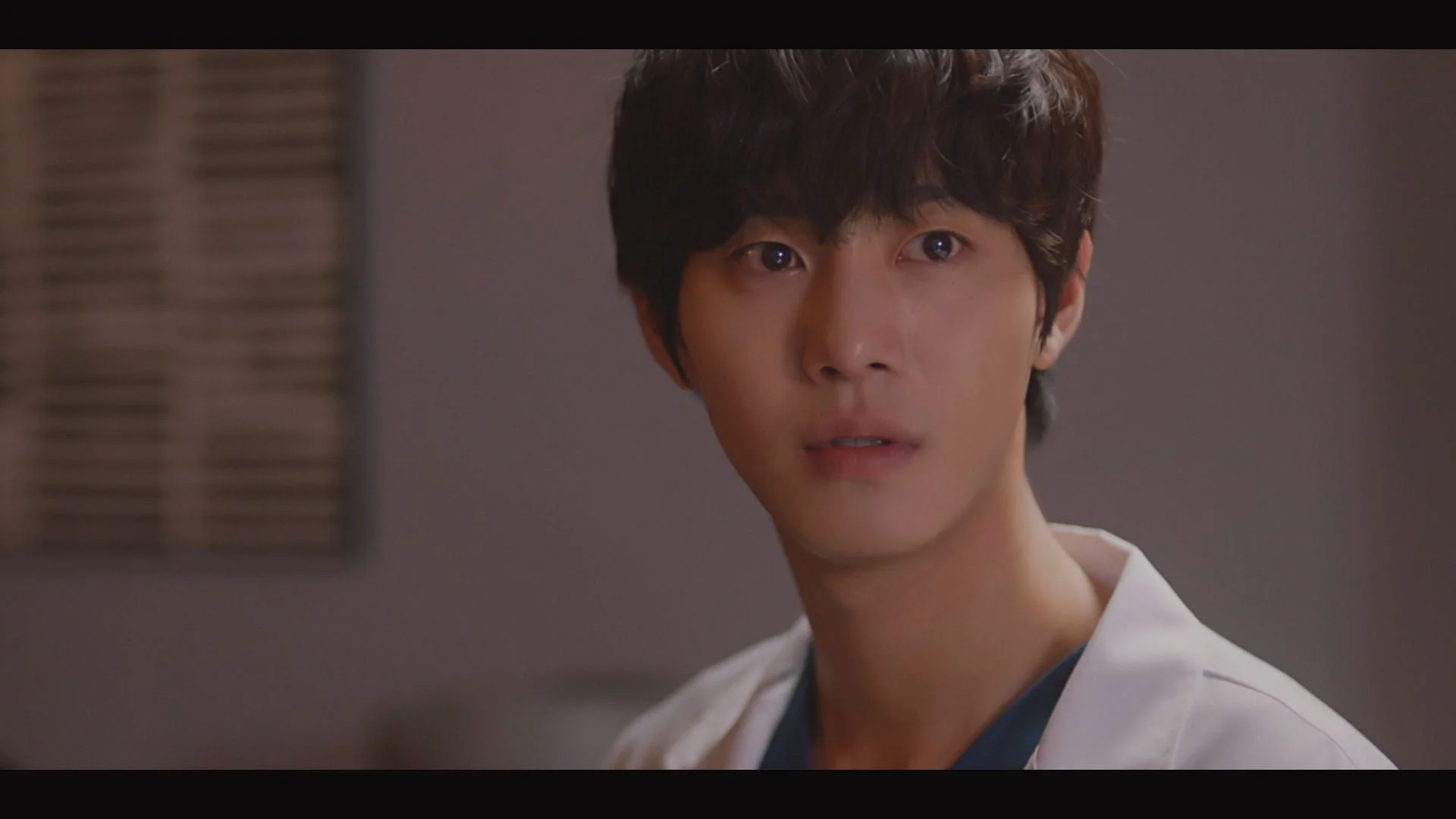 白衣を着た若いアジア人男性が真剣な表情