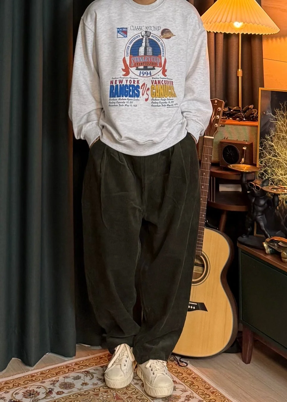 男性がヴィンテージ風スウェットとコーデュロイパンツを着用